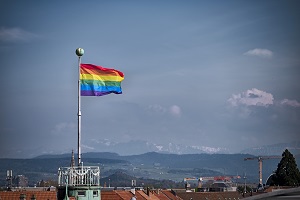 Regenbogenfahne am Fahnenmast über den Dächern der Stadt